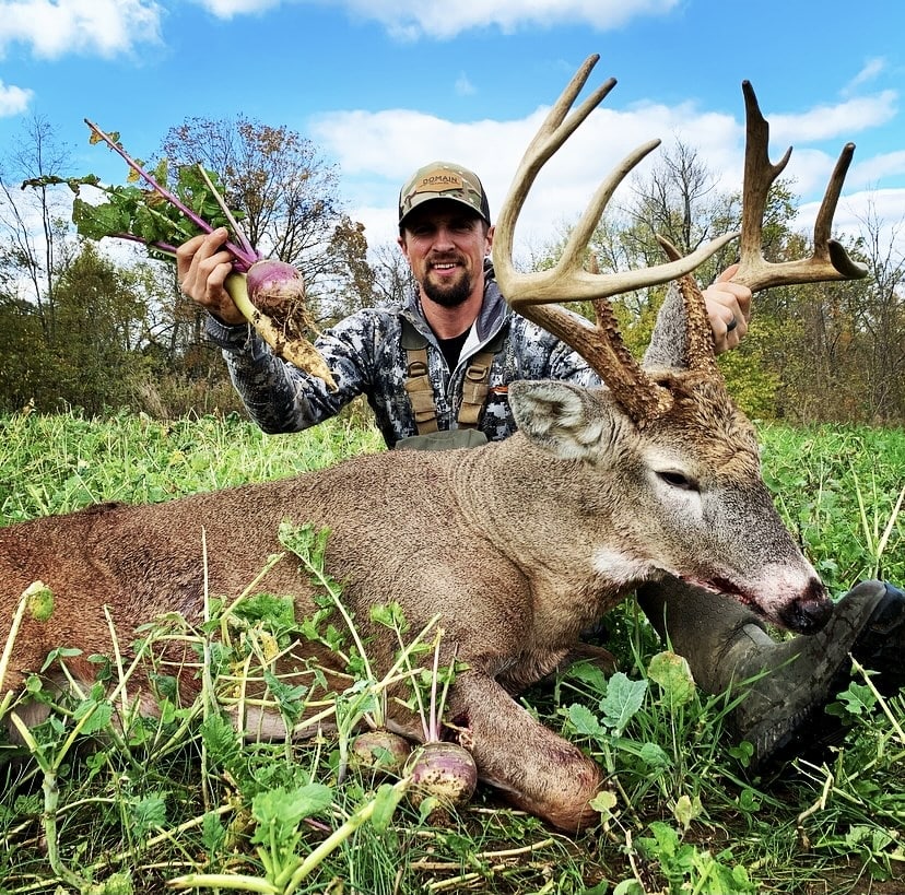 Hunter with a whitetail buck in his food plot